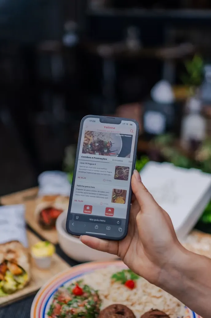 A hand holding a phone showing a food-ordering app.